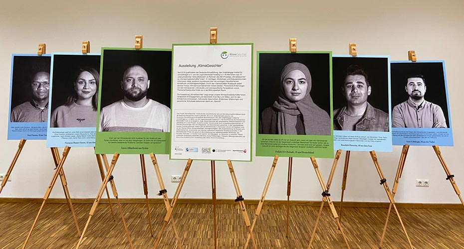 Fotos der Gesichter der Portraitausstellung über Klimaflucht stehen auf Staffeleien.