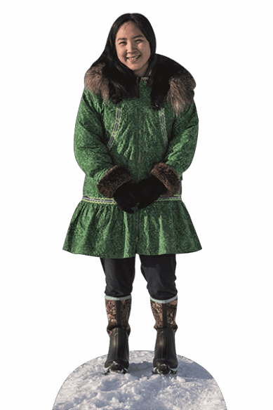 Eine junge Indigene aus Alaska steht in traditionellem Gewand im Schnee und lächelt.