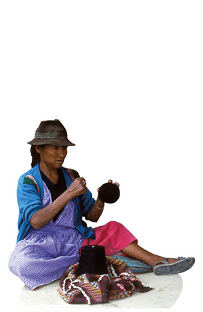 Eine Frau aus Bolivien sitzt auf dem Boden und hält eine Wollknäuel.