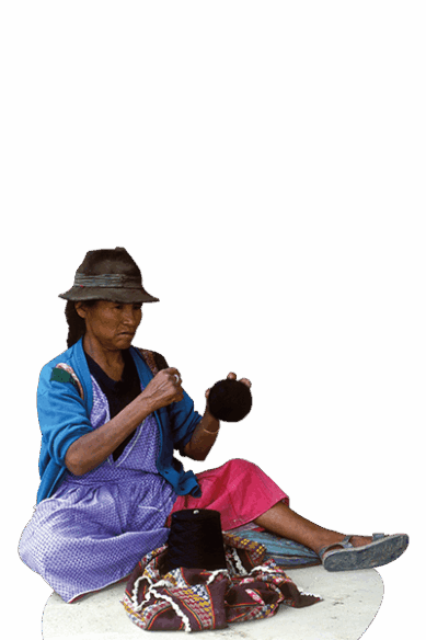 Eine Frau aus Bolivien sitzt auf dem Boden und hält eine Wollknäuel.