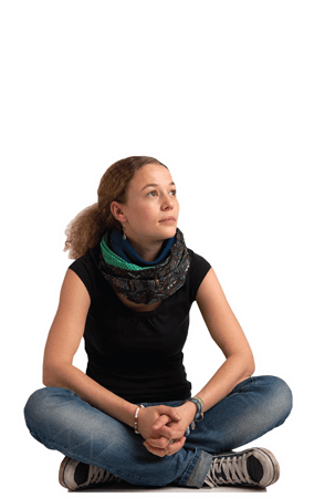Eine Jugendliche aus Deutschland sitzt auf dem Boden und blickt nach oben.