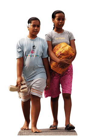 Zwei junge Frauen aus Kiribati sind mit einer Einkaufstasche auf der Straße unterwegs.