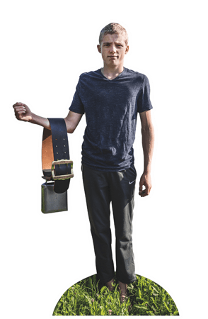 Ein junger Bergbauer aus der Schweiz steht auf der Weide und zeigt eine Kuhglocke.