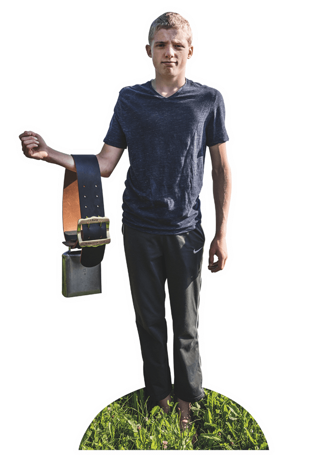 © Manolo Ty Ein junger Bergbauer aus der Schweiz steht auf der Weide und zeigt eine Kuhglocke.